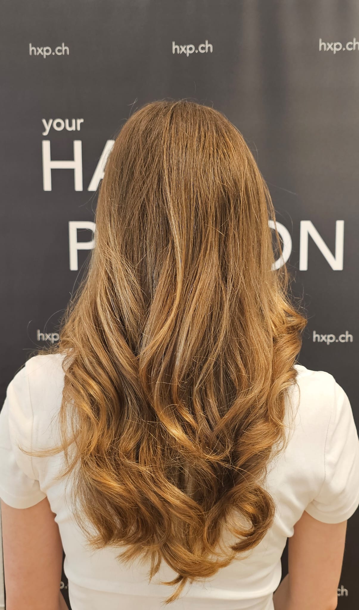 Lange karamellbraune Stufenfrisur – Rückansicht bei HairXperience
